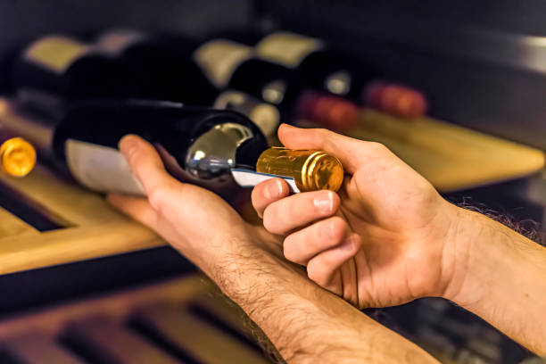 Homme qui sort une bouteille de vin de sa cave à vins